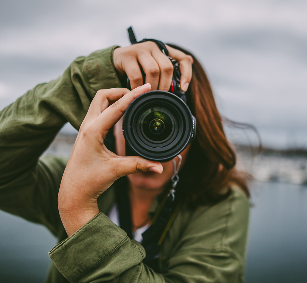 Person in grüner Jacke fotografiert mit einer Kamera im Hochformat